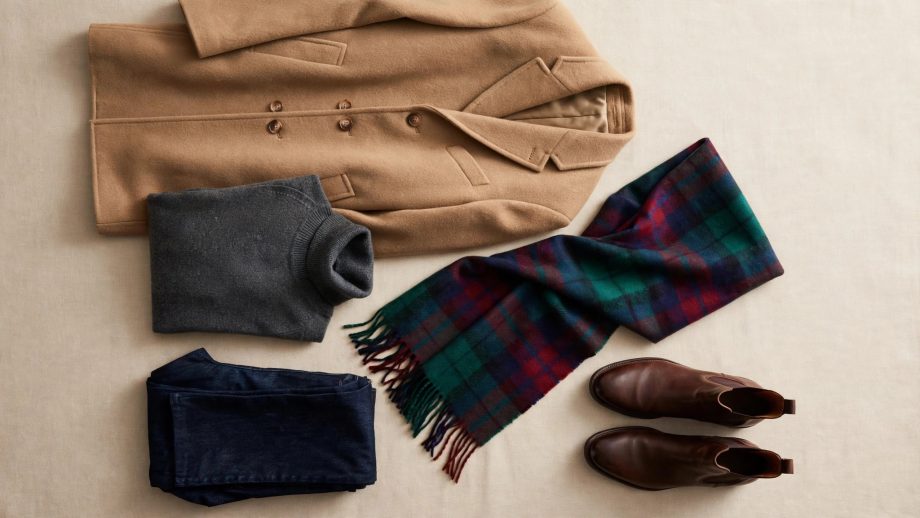 Men's winter fashion layering flat-lay with camel coat, turtleneck, plaid scarf, jeans and boots